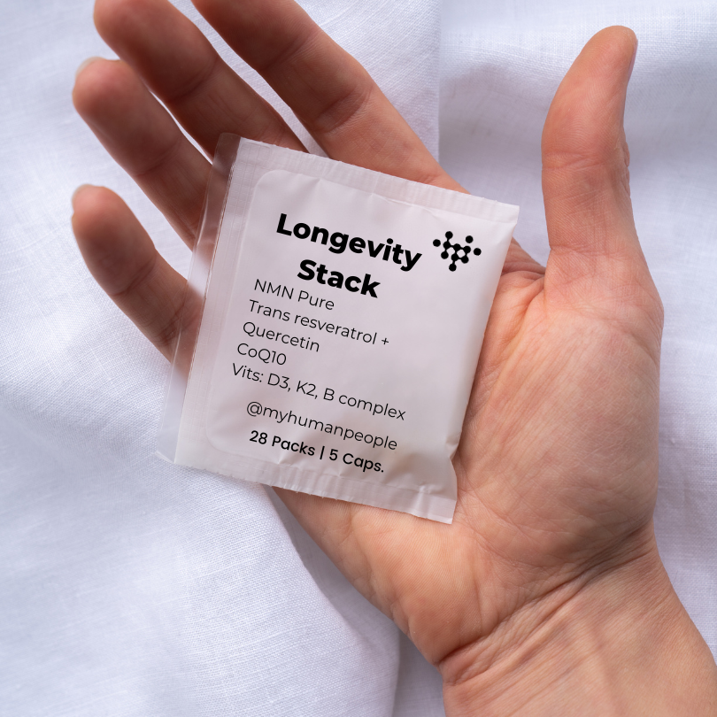 Image of a hand holding a humanpeople satchet. The writing says longevity stack, NMN Pure, trans resveratrol, quercetin, CoQ10, vits D3, K2, B complex. 28 packs 5 capsules