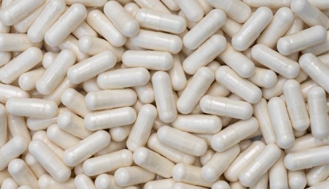 A dense collection of white allicin capsules filling the frame, indicative of health supplements and the benefits of garlic extract for wellness..
