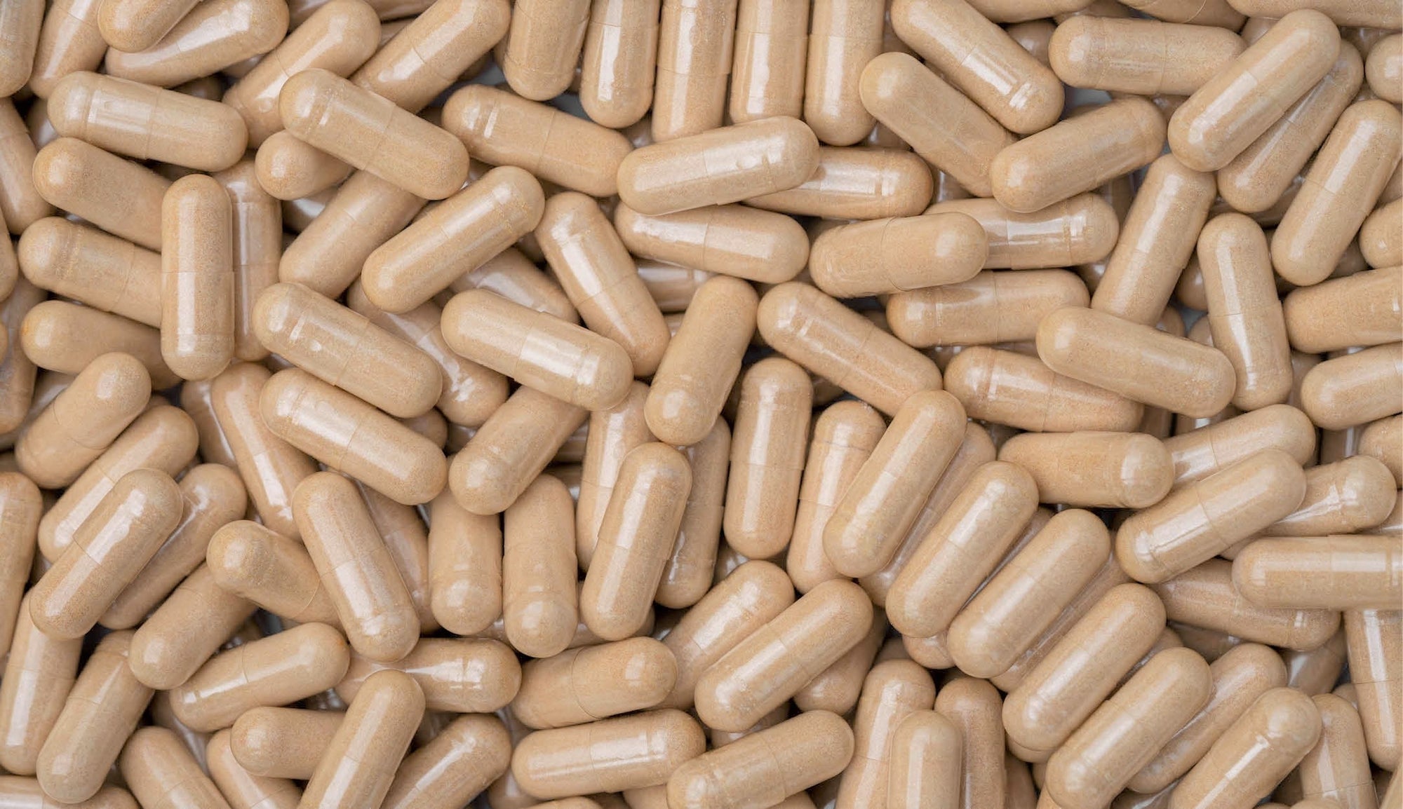 Pile of beige ashwagandha capsules, showcasing a natural herbal supplement commonly used for stress relief and vitality enhancement.