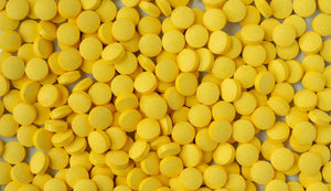 Numerous yellow B-complex vitamin tablets tightly packed, emphasizing the importance of balanced B vitamins in nutritional health and energy metabolism.