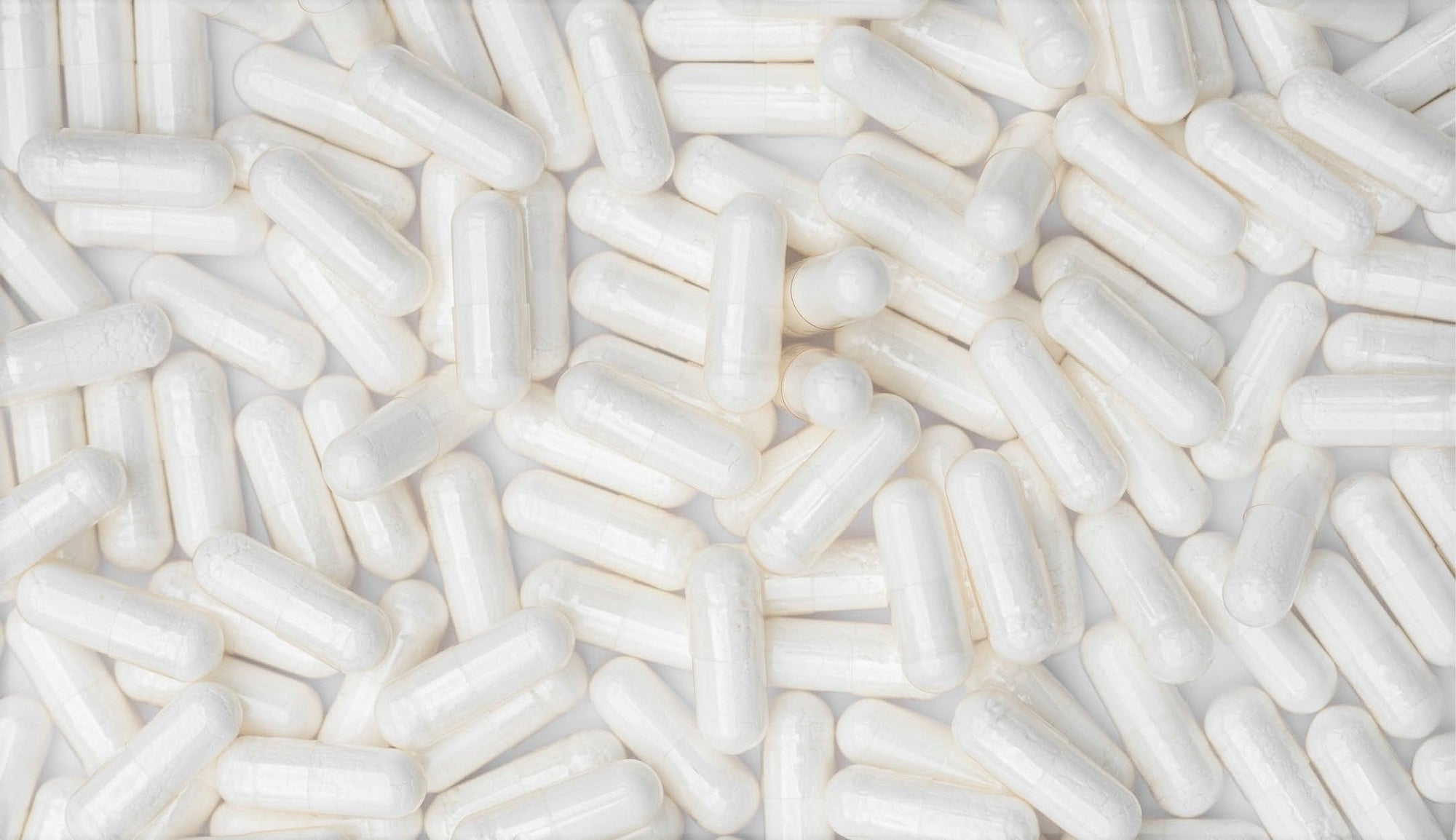 Overlapping white betaine HCL capsules covering the surface, indicating their role in promoting healthy digestive function and protein absorption.