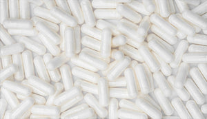 Overlapping white betaine HCL capsules covering the surface, indicating their role in promoting healthy digestive function and protein absorption.