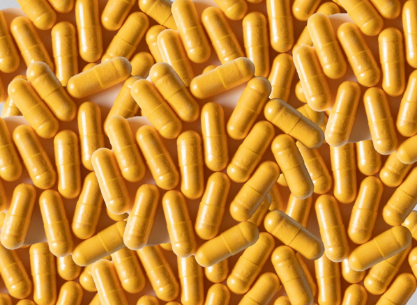 Multiple CoQ10 300mg yellow capsules piled together, showcasing a dietary supplement product for health and wellness.