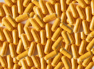 Multiple CoQ10 300mg yellow capsules piled together, showcasing a dietary supplement product for health and wellness.