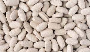 Detailed image of a multitude of beige cordyceps mushroom supplement tablets clustered together, showcasing the uniform shape and natural color variation indicative of the supplement's organic origin, commonly sought for immune support.