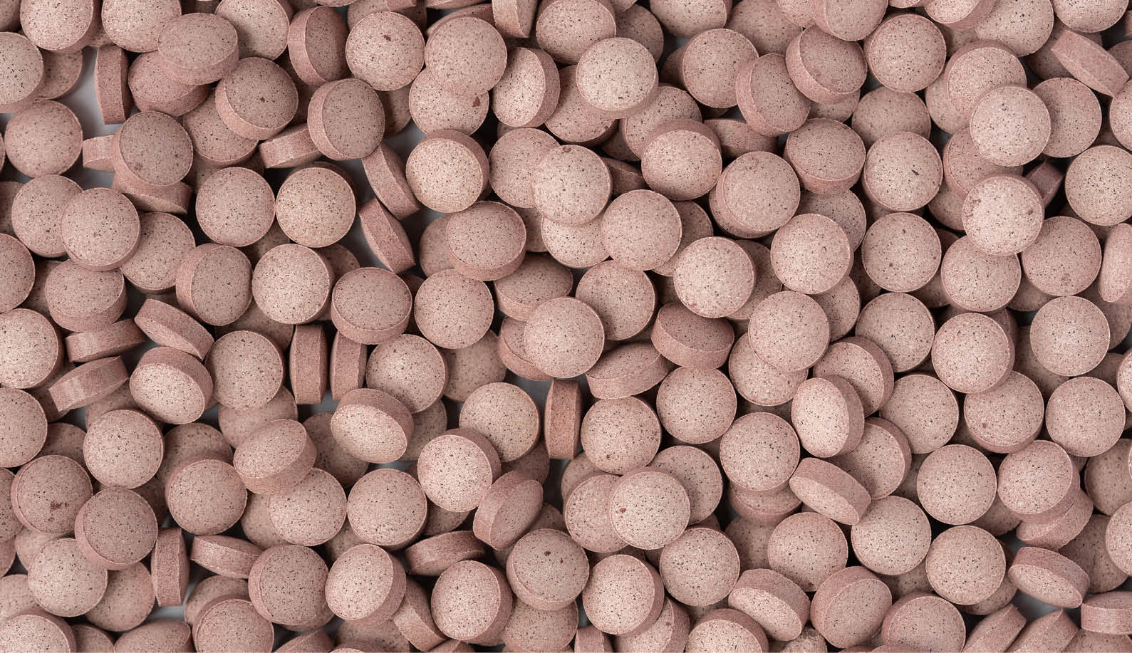 A dense array of pinkish-brown astaxanthin tablets, emphasizing the supplement's role in supporting skin health and overall antioxidant protection.