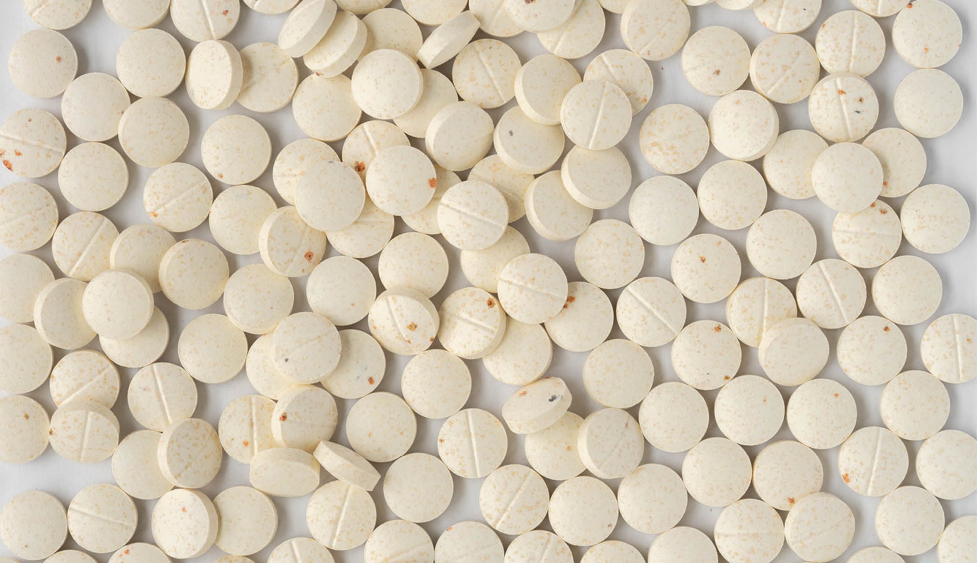 Scattered speckled tablets of an antioxidant booster supplement rich in vitamins A, C, and E, displayed as a health and wellness product.
