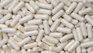Dense array of off-white DIM (Diindolylmethane) supplement capsules with a smooth finish, randomly scattered, highlighting the consistency in size and shape, intended for supporting hormonal balance and metabolic health.