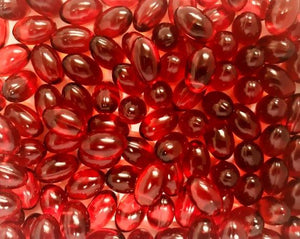 Cluster of glossy, translucent red krill oil softgel capsules, reflecting light and emphasizing the supplement's rich omega-3 fatty acid content, beneficial for heart and joint health.