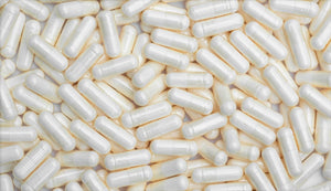 A dense spread of Lactobacillus fermentum probiotic capsules with a pearly sheen, overlapping one another to display their uniform capsule form.